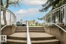 Concrete exterior staircase with white metal railings - 303 10528 77 Avenue, Edmonton, AB 