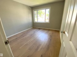 Room with light wood-finish flooring, neutral gray walls, and white baseboards - 