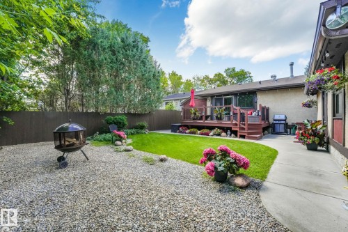 Expansive backyard featuring a gravel patio area, manicured lawn, and a multi-level wooden deck - 17237 104 Street, Edmonton, AB 