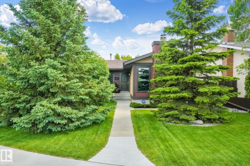 Front exterior featuring mature evergreen trees, a concrete walkway, a manicured lawn, and a multi-level roofline - 17237 104 Street, Edmonton, AB 