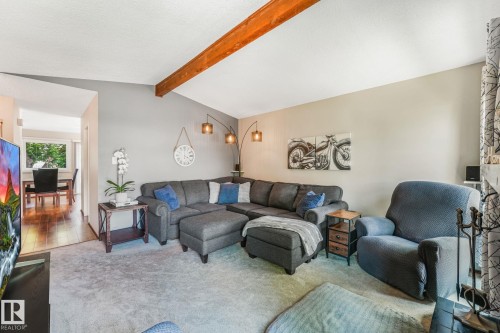 Living room featuring a vaulted ceiling with exposed wood beam, light grey wall tones, and neutral carpet flooring - 17237 104 Street, Edmonton, AB 