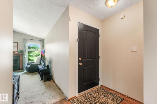 Entryway featuring a dark paneled door with brass hardware, wood-finish flooring, and a flush mount ceiling light - 17237 104 Street, Edmonton, AB 