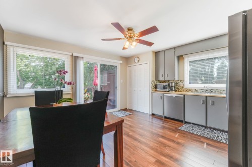 Open-concept kitchen and dining area featuring wood-finish flooring, grey cabinetry, and a mosaic tile backsplash - 17237 104 Street, Edmonton, AB 