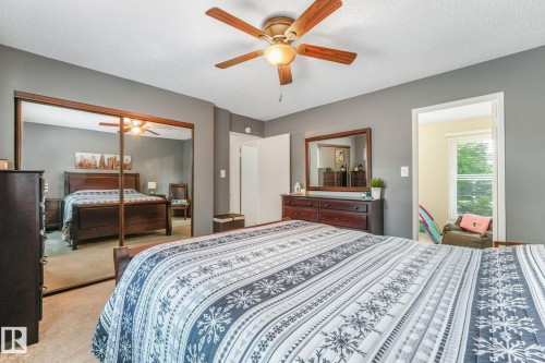 Bedroom featuring neutral gray walls, a ceiling fan with light fixture, carpeted flooring, and mirrored closet doors - 17237 104 Street, Edmonton, AB 