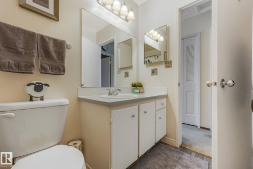 Bathroom featuring a single vanity with a white basin sink, polished chrome faucet, and a large wall-mounted mirror with an overhead light fixture - 17237 104 Street, Edmonton, AB 