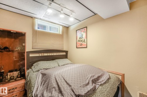 Bedroom featuring a drop ceiling with track lighting, a window with horizontal blinds, and neutral-toned walls - 17237 104 Street, Edmonton, AB 