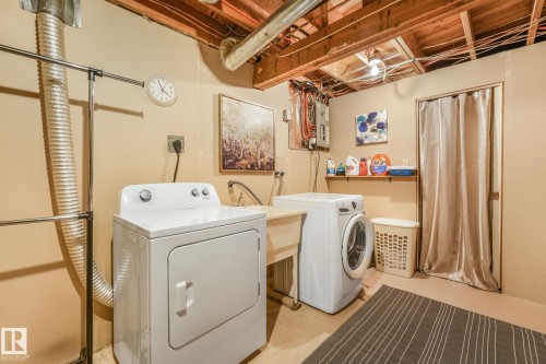 Dedicated laundry area featuring a white top-load washer, a white front-load dryer, and a utility sink - 17237 104 Street, Edmonton, AB 
