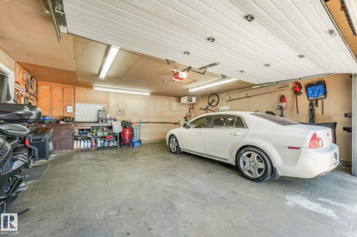 Spacious garage featuring a concrete floor, built-in cabinetry, and overhead fluorescent lighting - 17237 104 Street, Edmonton, AB 