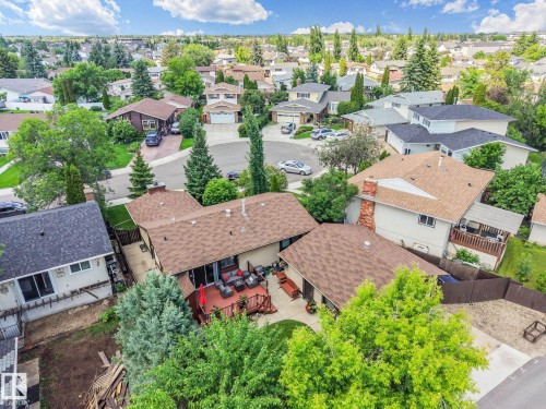 Expansive rear deck featuring a red umbrella, multiple seating arrangements, and direct access to the interior via a sliding glass door - 17237 104 Street, Edmonton, AB 