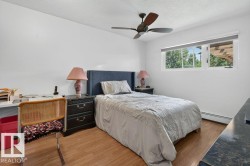 Bedroom featuring wood-finish flooring, a contemporary ceiling fan, and a window with a white frame - 