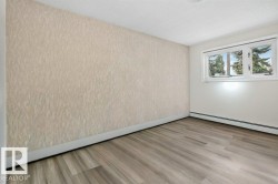 Room featuring wood-finish flooring, white baseboards, and a textured accent wall - 