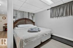 Bedroom featuring a decorative wood-finish accent wall, light grey walls, and light wood-look flooring - 