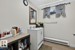 Bathroom featuring a white vanity with a rectangular sink, wood-finish flooring, and a baseboard heating unit - 