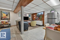 Finished basement space featuring a drop ceiling with wood-finish beam, light-toned wood-finish flooring, and a mix of tile flooring - 