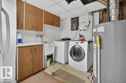 Dedicated utility room featuring wood-finish cabinetry, a utility sink, and white appliances - 