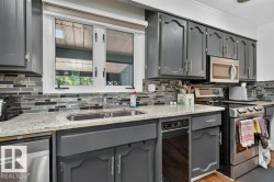 Kitchen featuring gray cabinetry, a double basin stainless steel sink, and light-toned countertops - 