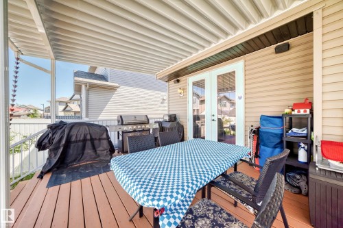 Expansive covered deck featuring wood-finish decking, white aluminum railings, and double glass-paneled doors - 12410 171A Avenue, Edmonton, AB 