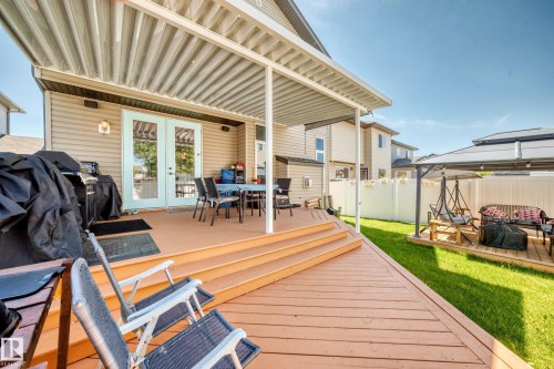 Expansive wood-finish deck with multiple levels, featuring a covered patio area and direct access to the interior via double French doors - 12410 171A Avenue, Edmonton, AB 