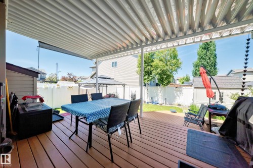 Expansive covered deck featuring wood-finish flooring, a white corrugated ceiling, and direct access to the fenced backyard - 12410 171A Avenue, Edmonton, AB 