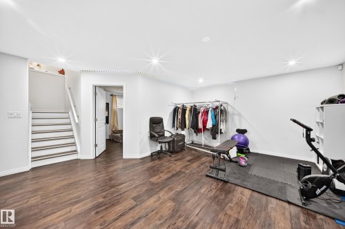 Spacious room featuring wood-finish flooring, recessed lighting, white walls, and a staircase with white risers and wood-finish treads - 12410 171A Avenue, Edmonton, AB 