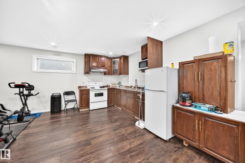 Kitchen area featuring wood-finish flooring, wood cabinetry, a white range, and a stainless steel sink with a gooseneck faucet - 12410 171A Avenue, Edmonton, AB 