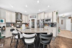 Kitchen featuring an angled island with a light-toned countertop, wood-finish flooring, recessed lighting, and white cabinetry - 