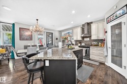 Kitchen featuring a central island with granite countertop and seating, stainless steel appliances, and wood-finish flooring - 
