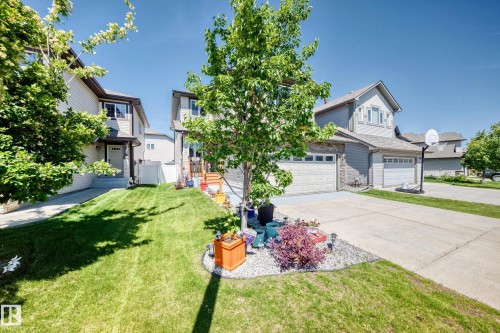 Residential exterior featuring a manicured lawn, concrete driveway, attached garage, and mature landscaping - 12410 171A Avenue, Edmonton, AB 