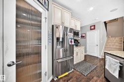 Kitchen area featuring wood-finish flooring, light-toned cabinetry, stainless steel appliances, and granite-style countertops - 