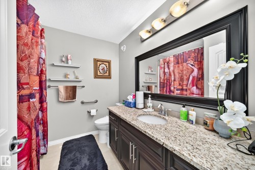 Single vanity with an integrated sink, speckled countertop, and dark wood cabinetry - 12410 171A Avenue, Edmonton, AB 