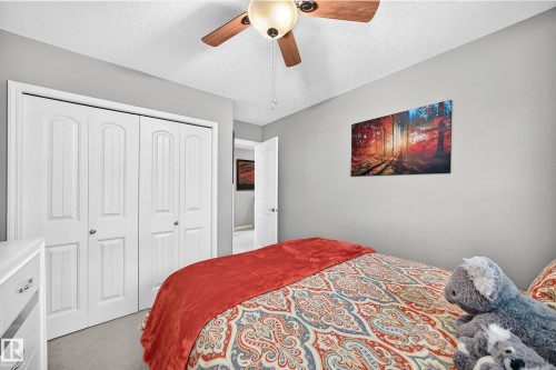 Bedroom featuring light gray walls, plush carpet flooring, a ceiling fan with integrated lighting, and white bi-fold closet doors - 12410 171A Avenue, Edmonton, AB 