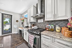 Kitchen featuring wood-finish flooring, shaker-style cabinetry, granite countertops, and a full tile backsplash - 