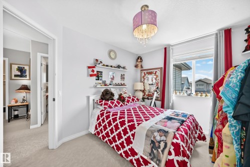 Bedroom featuring a double-pane window, neutral wall paint, and light-toned carpet flooring - 12410 171A Avenue, Edmonton, AB 