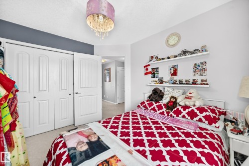 Recessed lighting with a decorative chandelier, dual white bi-fold closet doors, white wall shelving, and neutral carpeting - 12410 171A Avenue, Edmonton, AB 