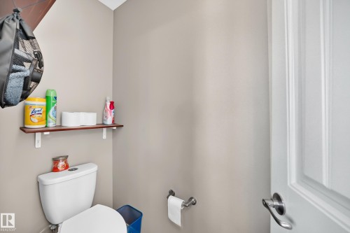 White toilet with a built-in toilet paper dispenser and a wood-finish shelf - 12410 171A Avenue, Edmonton, AB 