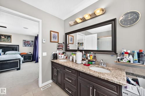 Double vanity with granite-finish countertop, dual undermount sinks, and dark wood cabinetry - 12410 171A Avenue, Edmonton, AB 