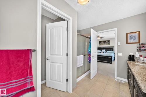 Bathroom with tiled flooring, a glass-enclosed shower, and a vanity featuring a granite-style countertop and dark wood-finish cabinetry - 12410 171A Avenue, Edmonton, AB 