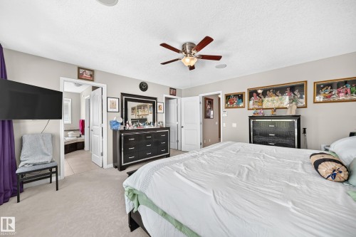 Carpeted bedroom featuring a ceiling fan, recessed lighting, and a doorway opening to a tiled bathroom with a built-in tub - 12410 171A Avenue, Edmonton, AB 