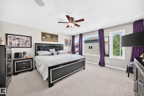 Spacious bedroom featuring light neutral wall tones, light carpet flooring, and a ceiling fan with integrated lighting - 12410 171A Avenue, Edmonton, AB 