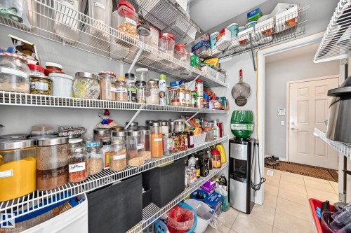 Spacious pantry featuring extensive wire shelving, tiled flooring, and a paneled interior door - 12410 171A Avenue, Edmonton, AB 