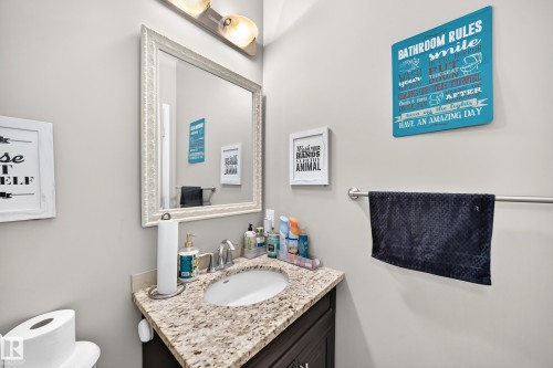 Bathroom vanity featuring a light-toned countertop with integrated sink, chrome faucet, and dark wood-finish cabinetry - 12410 171A Avenue, Edmonton, AB 