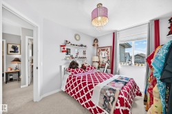 Bedroom featuring a double-pane window, neutral wall paint, and light-toned carpet flooring - 