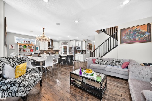 Open-concept living space featuring wood-finish flooring, recessed lighting, and a prominent staircase with dark railings - 12410 171A Avenue, Edmonton, AB 