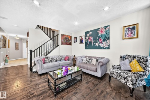 Living area featuring wood-finish flooring, recessed lighting, and a staircase with black railings - 12410 171A Avenue, Edmonton, AB 