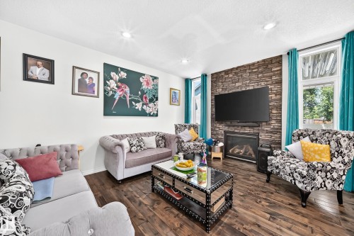 Spacious living area featuring wood-finish flooring, recessed lighting, and a stone accent wall - 12410 171A Avenue, Edmonton, AB 