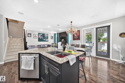Kitchen island with a granite countertop, double basin sink, and integrated dishwasher - 12410 171A Avenue, Edmonton, AB 