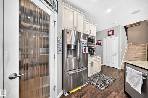 Kitchen area featuring wood-finish flooring, light-toned cabinetry, stainless steel appliances, and granite-style countertops - 12410 171A Avenue, Edmonton, AB 