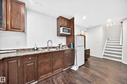 Kitchenette featuring rich brown cabinetry with ample storage, a double basin stainless steel sink, and a microwave - 