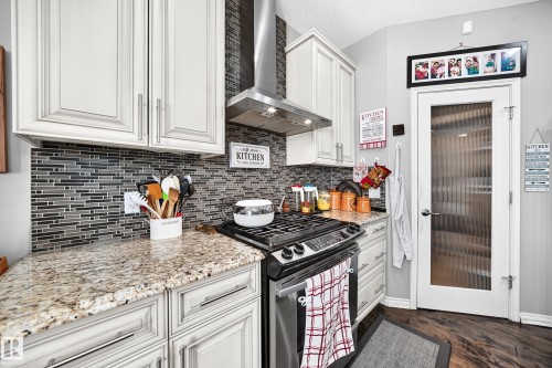Kitchen featuring light-toned cabinetry, a mosaic tile backsplash, and granite-style countertops - 12410 171A Avenue, Edmonton, AB 