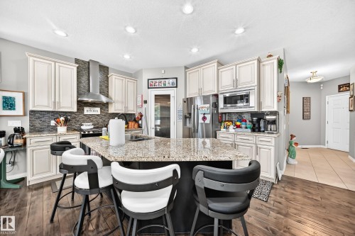 Kitchen featuring an angled island with a light-toned countertop, wood-finish flooring, recessed lighting, and white cabinetry - 12410 171A Avenue, Edmonton, AB 